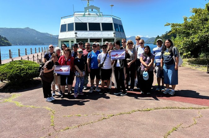 Sunrise Tours group posing on the pier in front of the Lake Ashi sightseeing boat